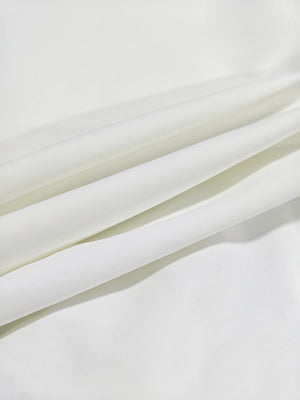 Close-up texture of white women's regular fit stretchy golf pants fabric showing detailed stretchy material and weave.