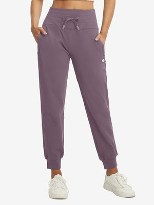 Model wearing women's stretch fleece lined water resistant joggers in light pinkish purple, showcasing the front lower body view.