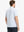 Rear half-body view of model in WHITE/LIGHT BLUE STRIPE golf-ready polo