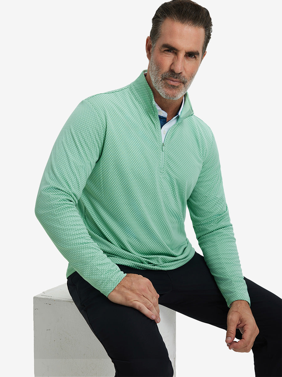 Model sitting and wearing jacquard quarter zip pullover in light green, showing relaxed casual posture.