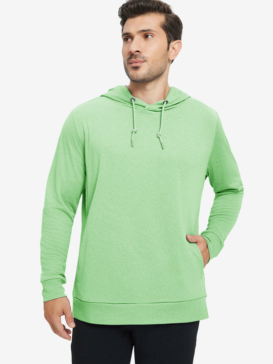 Model with one hand in pocket, wearing classic heather pullover hoodie in light green melange, relaxed look.