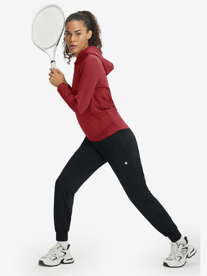 Model holding tennis racket while wearing women's lightweight hoodies pullover in red.