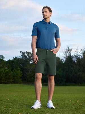 Model standing on course with one hand in pocket, wearing 4-way stretch performance solid shorts in olive green