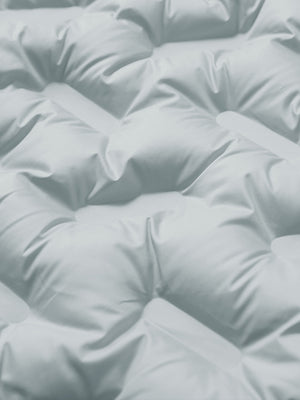 Fabric close-up of boys windproof puffer jacket with pockets, highlighting texture and finish in light grey.