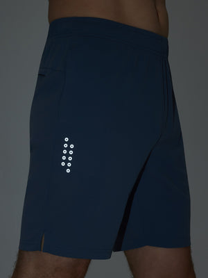 Detail of glow in the dark feature on misty blue breathable running shorts with 4 zipper pockets