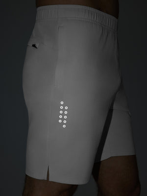 Detail of glow in the dark feature on white breathable running shorts with 4 zipper pockets