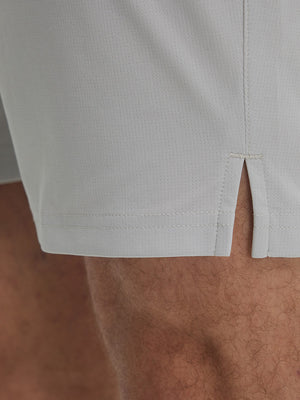 Detail view of hem on khaki grey breathable running shorts with 4 zipper pockets
