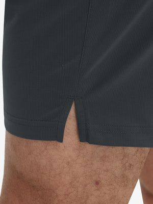 Detail view of hem on dark grey breathable running shorts with 4 zipper pockets