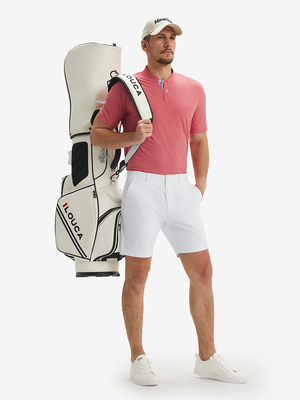Full-body front view: model in brick red moisture-wicking short sleeve henley shirt carrying golf bag.