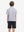 Back half-body view of youth wearing white purple shark performance print boys golf polo, showing rear design